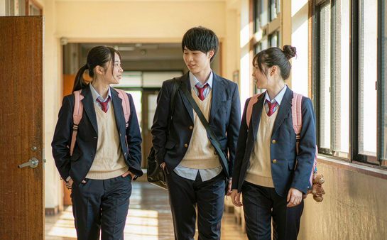 三名学生背着书包走在校园走廊